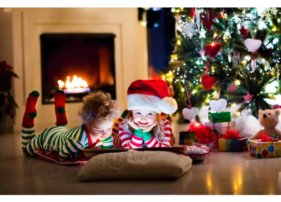 Children reading a book with a Christmas tree in the background.