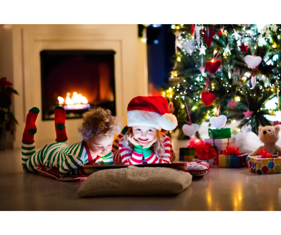 Children reading a book with a Christmas tree in the background.